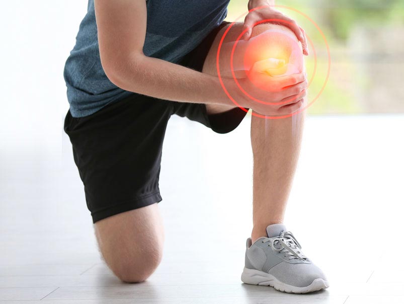 The bottom half of a man wearing sports clothes and kneeling on one knee while holding the other knee with his hands  and the area around his knee where he is holding it is highlighted in yellow and red circle showing that the man has discomfort because of his knee and he will need a professional chiropractor to help care for his knee discomfort that will help him with mobility and well being.
